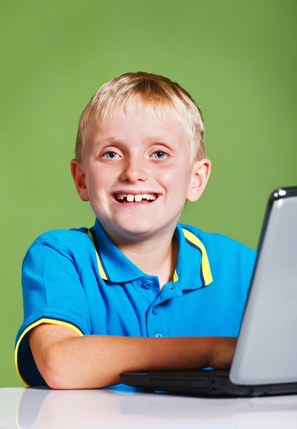 Smiling blond schoolboy with open laptop computer