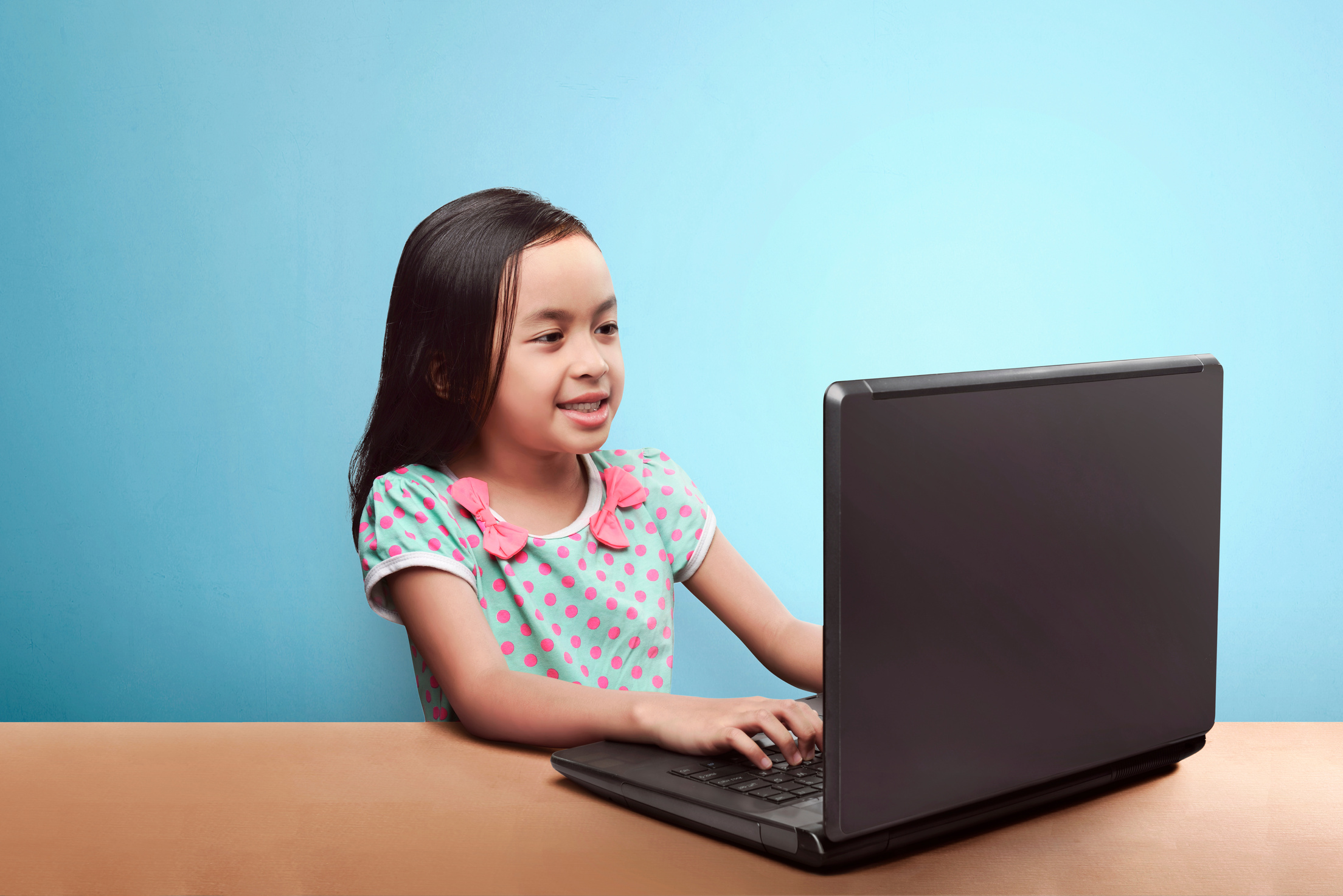 Smiling asian child with laptop computer on the table