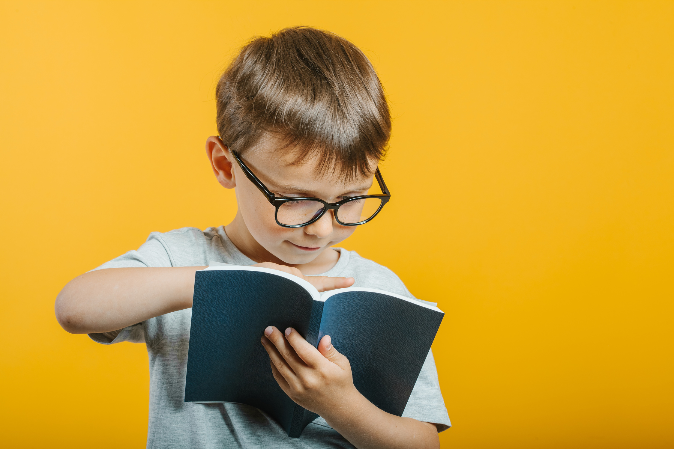 child reads a book against a bright wall