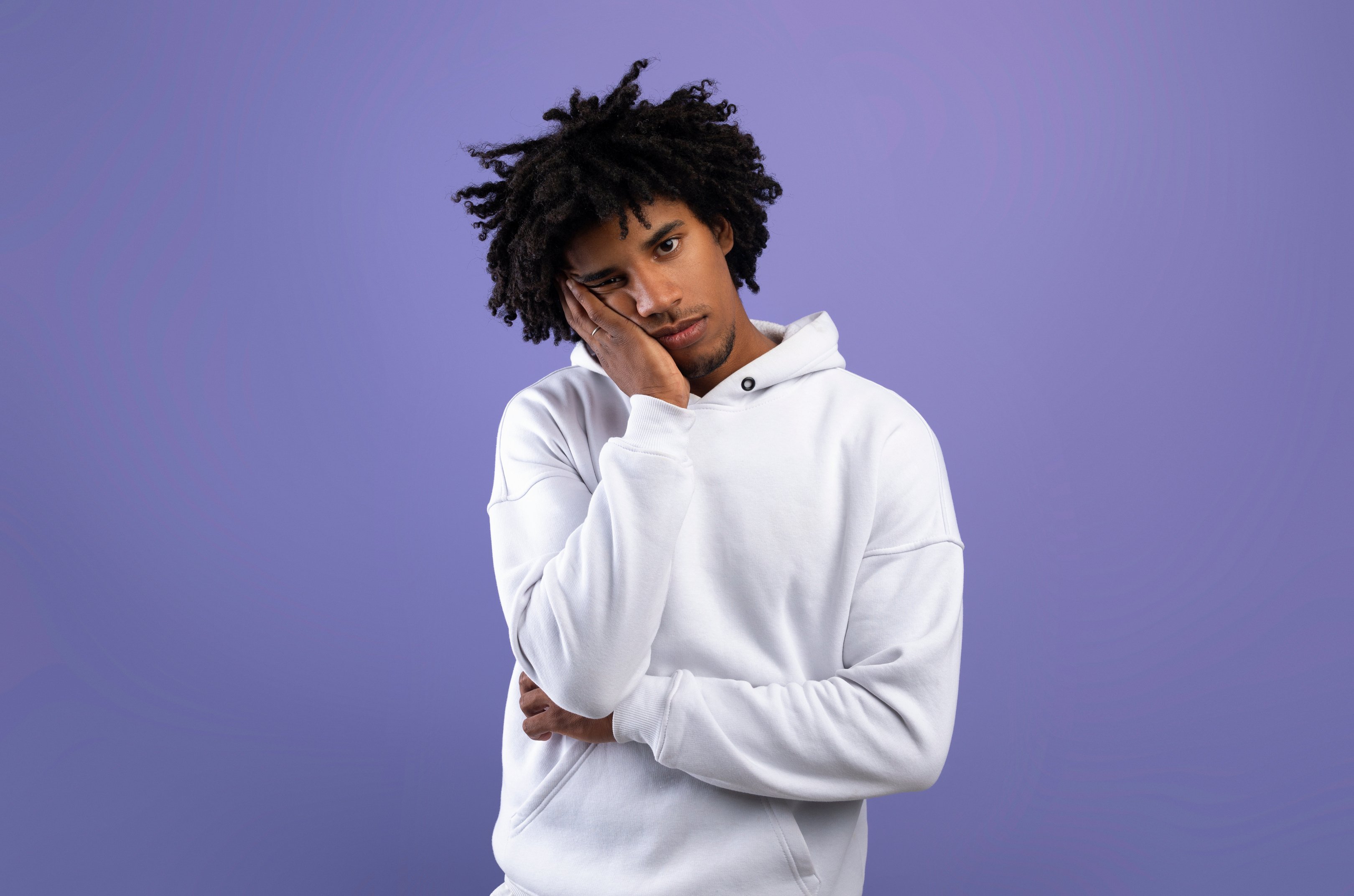 Portrait of Black Teen Guy Feeling Bored, Leaning on His Hand, Having Dull Day on Violet Studio Background